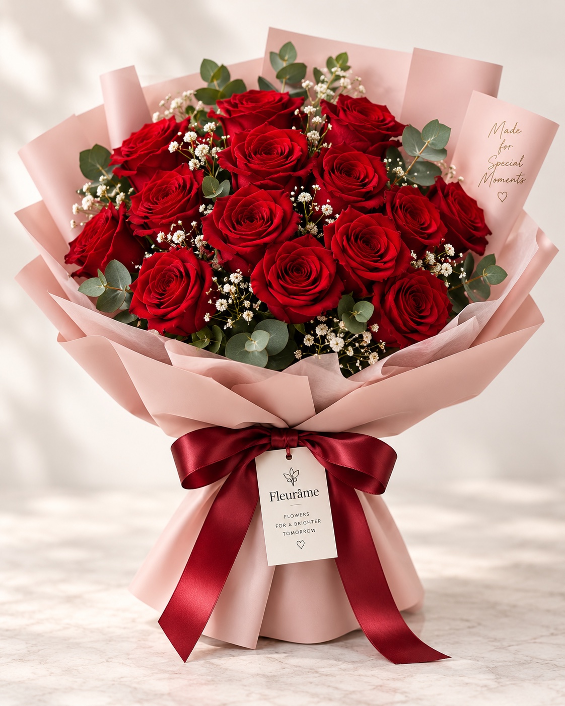Full bouquet of deep red roses wrapped in blush paper with a burgundy ribbon